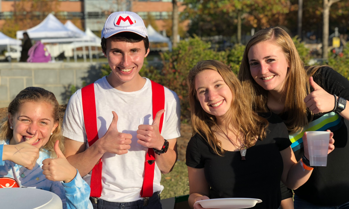 Three female and one male students with thumbs up.