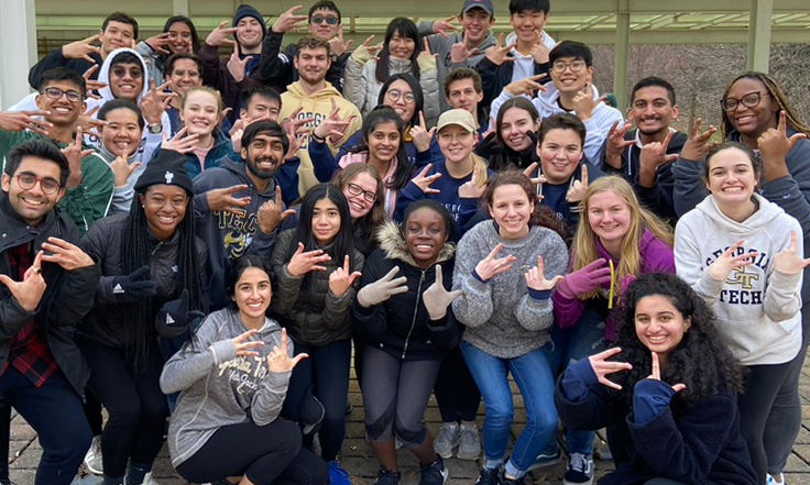 A big group of students grouped together smiling to the camera.