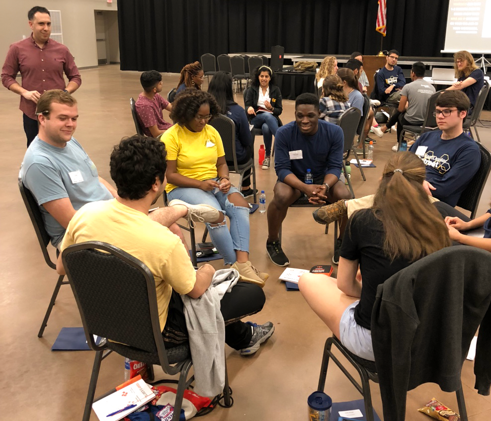 A group of students sit in a discussion circle.