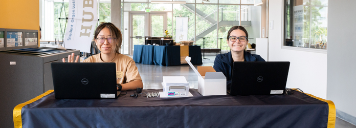 2 student assistants sit at a help desk at the center for student engagement